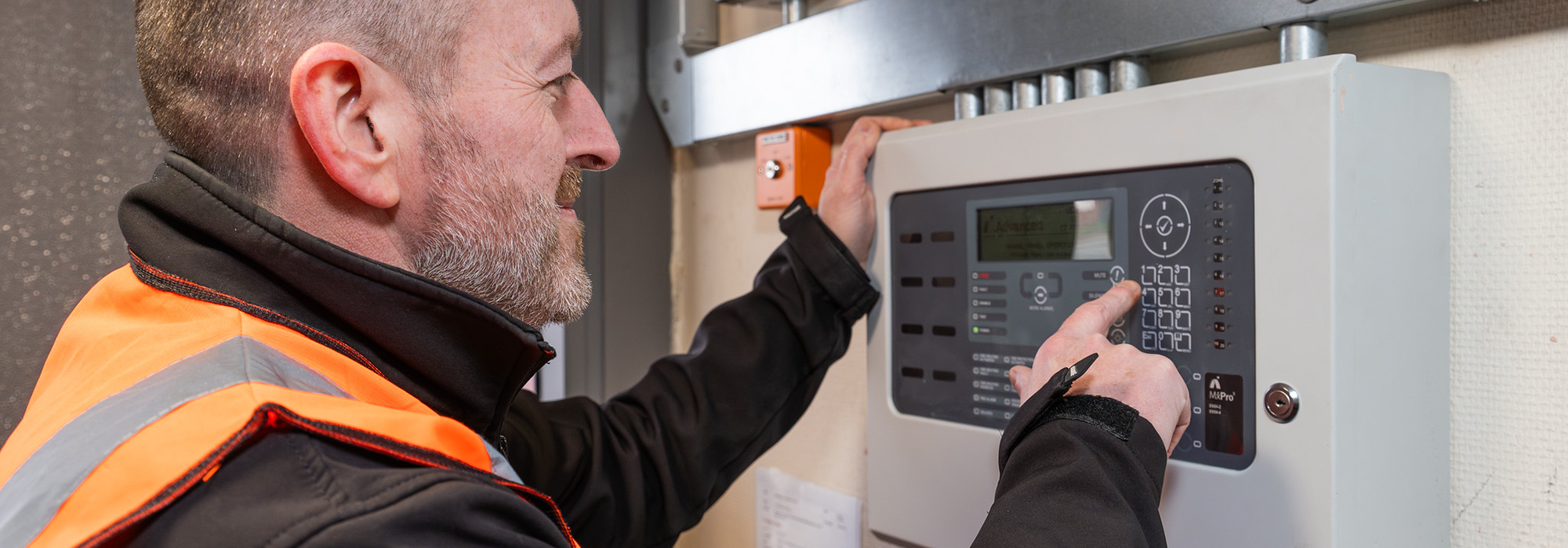 operative in orange high vis vest testing newly installed alarm system